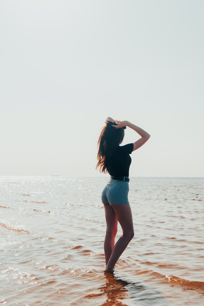 woman in blue denim shorts standing on beach during daytime
